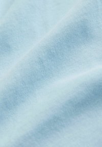 Helles blaues Gewebe mit feiner Strickstruktur und sanften Falten, die weiche Schatten und Highlights erzeugen.