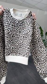 Sweatshirt com padrão de leopardo em tecido suave, com mangas longas, gola e punhos canelados em ivori, apresentando um corte descontraído e ombros caídos.