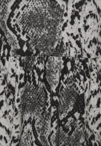 Tissu à imprimé serpent noir et gris avec une apparence texturée, présentant un motif et des drapés doux et fluides.