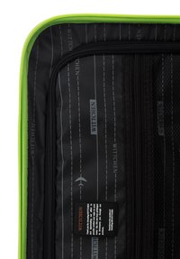 Maleta de viaje negra con un vibrante zipper verde en su interior. El revestimiento interior presenta un patrón de logotipos repetidos y un bolsillo de malla con una etiqueta.