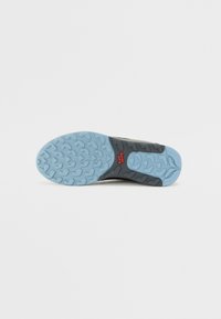Sneakersålen har en lyseblå gummibunn med et teksturert hjerte mønster, svarte detaljer, og en rød logo.