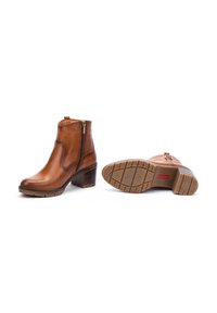 Botas de cuero marrón hasta el tobillo con cremallera lateral, tacón resistente y suela de goma texturizada. Diseño clásico con acabado suave y costuras sutiles.