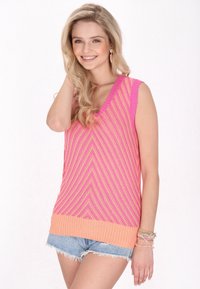 Rosa och persiko färgad ärmlös stickad topp med ett chevronmönster, med V-urringning och ribbad fåll. Matchad med denimshorts och armband.