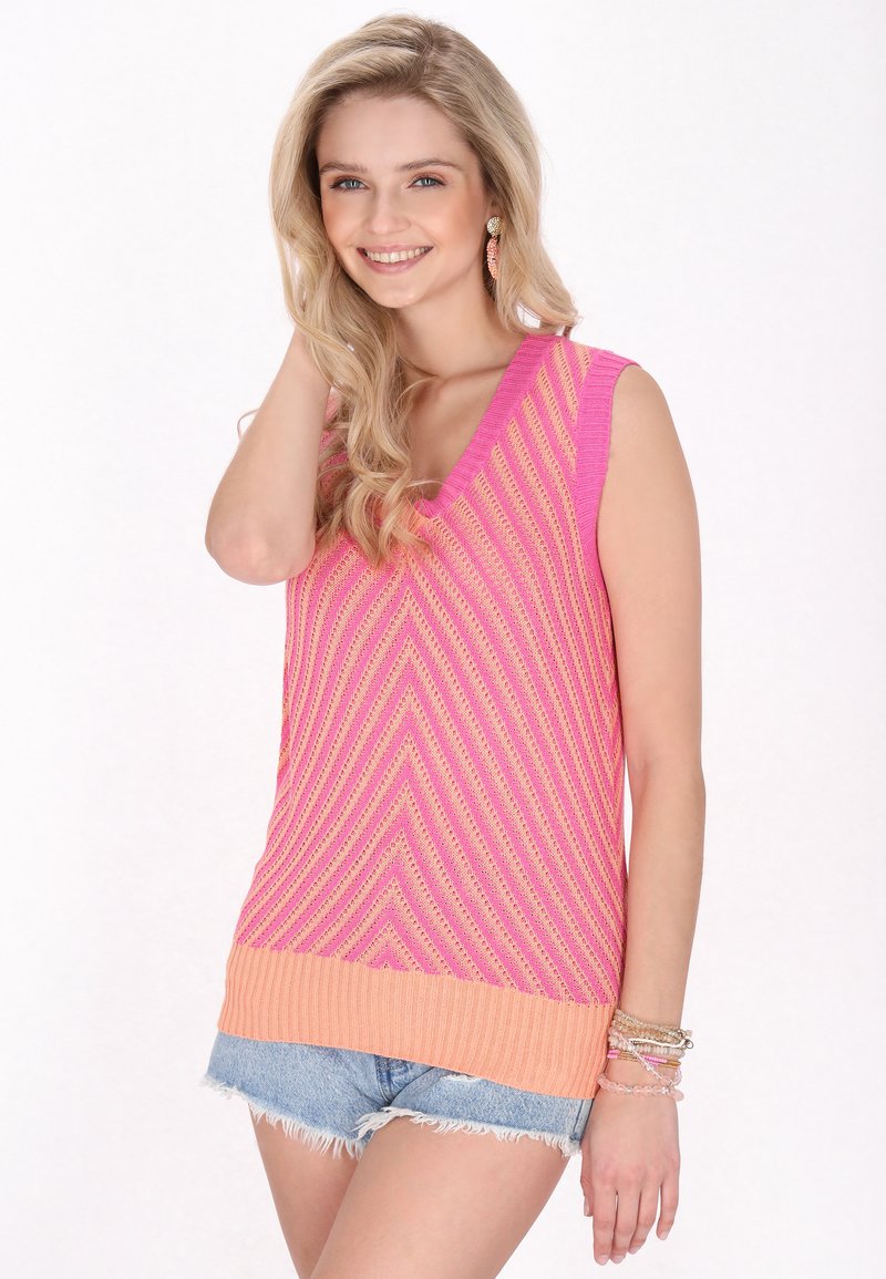 Rosa och persiko färgad ärmlös stickad topp med ett chevronmönster, med V-urringning och ribbad fåll. Matchad med denimshorts och armband.