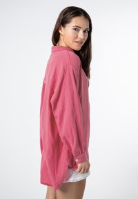 Overmaat, blouse met lange mouwen in zachtroze stof met een gestructureerde afwerking, voorzien van een kraag en knoopmanchetten.