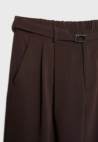Pantalon taille haute marron foncé avec plis à l'avant, poches latérales et ceinture en tissu assortie avec petite boucle argentée.