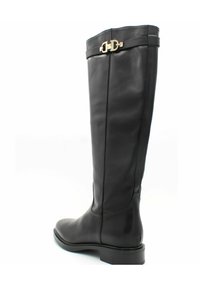 Botte noire en cuir, arrivant jusqu'au genou, avec une texture lisse, une semelle plate et un accent en métal doré sur la sangle supérieure. Présente un design élégant et ajusté.