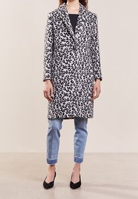 Leopardprint jas, gemaakt van zachte stof, heeft een geknipte kraag, een enkelvoudige sluiting en komt tot halverwege de bovenbenen. Draagt met een strak jeans.
