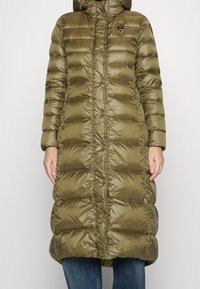 Abrigo acolchado de color verde oliva, con capucha, cierre de botones y diseño acolchado. Hecho de material brillante y suave con una silueta larga.