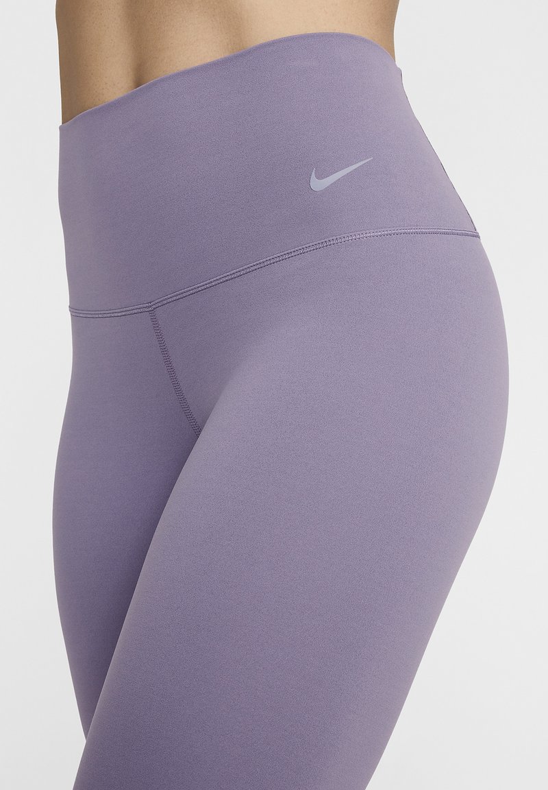 Leggings viola a vita alta realizzati in un materiale liscio ed elastico, con un discreto logo Nike sulla cintura e cuciture piatte.