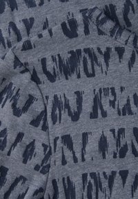 Tela gris con un patrón abstracto en azul oscuro que presenta diferentes texturas, costuras superpuestas y un aspecto suave y de punto.