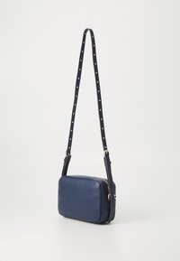 Borsa a tracolla in pelle blu navy con forma rettangolare, cinturino regolabile con borchie dorate e chiusura con zip. Texture liscia e design sobrio.