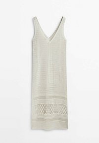 Robe en maille beige sans manches avec col en V et détail en maille ajourée à motifs près de l'ourlet, suspendue sur un fond blanc.