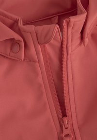 Rote Softshell-Jacke mit hohem Kragen, Reißverschluss und Druckknöpfen; glatte Textur mit kontrastierenden Nähten und YKK-Reißverschluss.