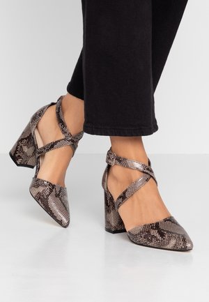 Puntige hakken met een slangenprint. Heeft kruisbanden rond de enkel en een blokhak. Kleurenpalet omvat tinten bruin en grijs.