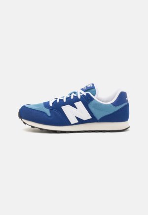 Blauwe en lichtblauwe sportieve sneaker met witte veters en een "N" logo, witte tussenzool en zwarte buitenzool op een effen witte achtergrond.