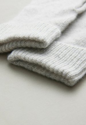 Pehme, volditud hall kootud kangas, näidates paksu soonikutega mansette, puhkamas siledal heledal pinnal.