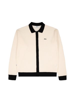 Cremefarbener Strickcardigan zum Knöpfen mit schwarzem Kragen, Bündchen und Saum sowie einem kleinen "obey"-Logo auf der linken Brustseite.