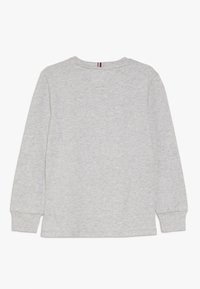 Langärmliges graues T-Shirt aus weichem, strukturiertem Material. Verfügt über einen Rundhalsausschnitt und gestickte Bündchen mit einem dezenten farblichen Akzent auf der Rückseite.