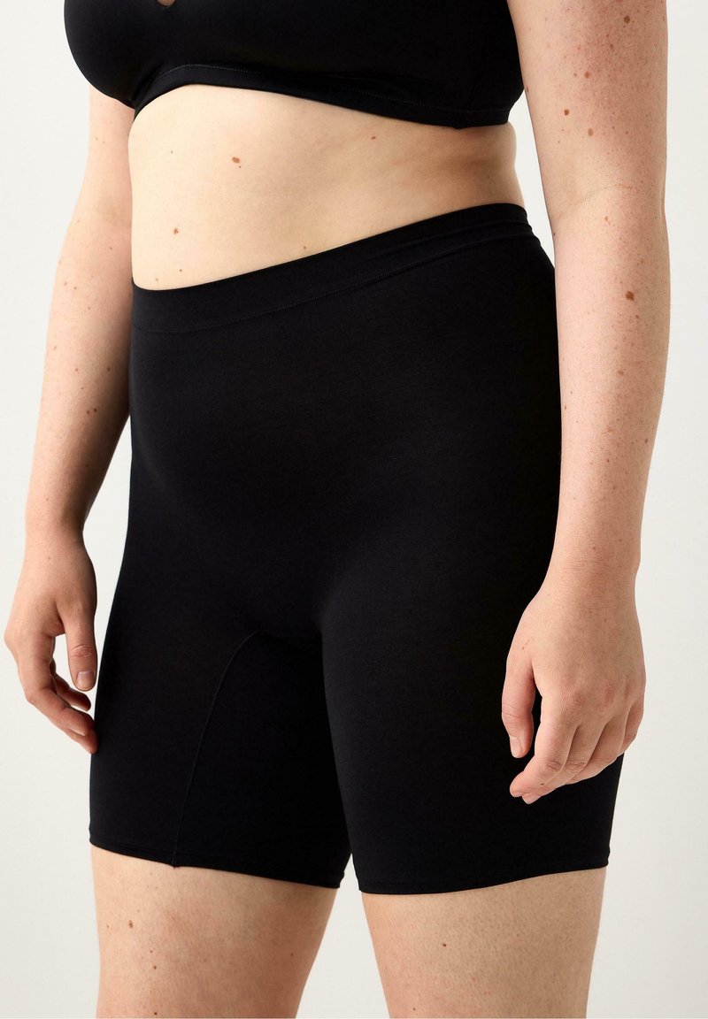 Schwarze, hochtaillierte Shorts aus dehnbarem Material, mit glatter Textur und elastischem Bund, entworfen für Komfort und Bedeckung.