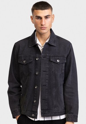 Chaqueta de denim negra con dos bolsillos en el pecho, herrajes plateados y un cuello clásico. Presenta un cierre de botón en la parte delantera y un ajuste relajado.