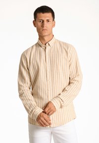 Gestreept overhemd in beige en wit, gemaakt van lichte stof. Heeft een kraag en lange mouwen met knoopmanchetten.