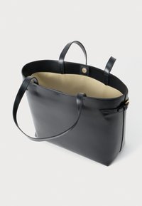 Schwarze Leder-Shopper-Tasche mit zwei Griffen, einem geräumigen beigen Innenraum und einem Knopfverschluss. Mit klaren Linien und einem minimalistischen Design.