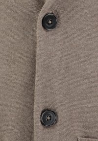 Lichtbruin gebreid cardigan met twee zwarte knopen, een gladde textuur en een gestikt zakje. Eenvoudig, klassiek ontwerp zonder patronen.