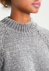 Grauer, strukturierten Pullover mit hohem, geripptem Kragen, aus einem plüschigen, weichen Stoff und Raglanärmeln für eine lockere Passform.