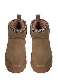 Pár hnědých semišových kotníkových bot s koženým podšívkou a vzorovaným lemováním, ploché gumové podrážky a poutka na zadní straně.