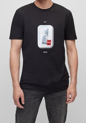 Czarna bawełniana koszulka z grafiką przedstawiającą vintage'owy telefon w białej ramce. Napis brzmi "DOPIERO PRZYSZEDŁO" oraz "KRUCHY" pod obrazkiem.