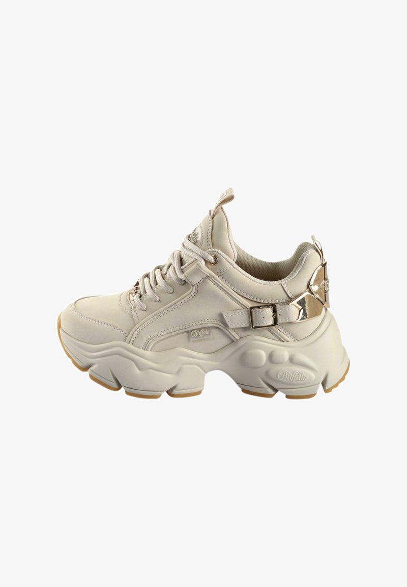 Beige sneakers laget av syntetisk materiale, med en kraftig såle, snøring og en gullfarget aksentstropp på siden.