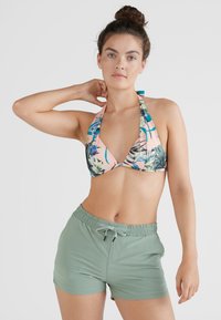 Top de bikini multicolorido com padrão floral e alças atrás do pescoço, combinado com calções de banho verdes sólidos com faixa elástica e cordão.