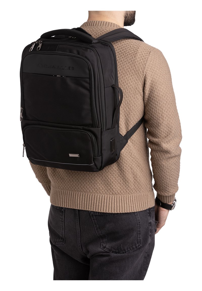 Zwarte rugzak van duurzaam materiaal, met meerdere met rits afgesloten vakken, gewatteerde schouderbanden en een slank rechthoekig ontwerp.