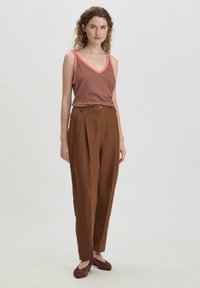 Bruine linnen hoge taillebroek met plooien en een knoopdetail, gecombineerd met een gestreept mouwloos topje in bruin- en tinten roze.