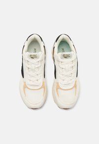 White sneakers with black accents and beige detailing. Mesh upper, lace-up design, padded collar, rubber sole. Brand name "HI-TEC" visible.