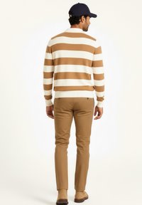 Suéter a rayas marrón y blanco, diseño ajustado, material de mezcla de algodón, combinado con pantalones beige ajustados y zapatos marrones, visto desde la espalda.