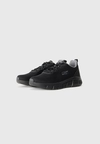 Black athletic shoes with mesh upper, lace-up design, padded collar, and textured rubber outsole. Features a subtle logo on the side.