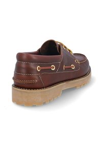 Zapato de bote de cuero marrón con ojales dorados, costuras en contraste y una suela de goma texturizada. Presenta un perfil bajo y una punta redondeada.
