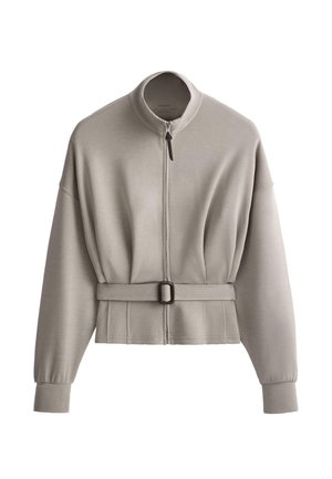 Jachetă cu fermoar și mâneci lungi, gri deschis, cu guler înalt și curea reglabilă în talie, confecționată dintr-un material moale.