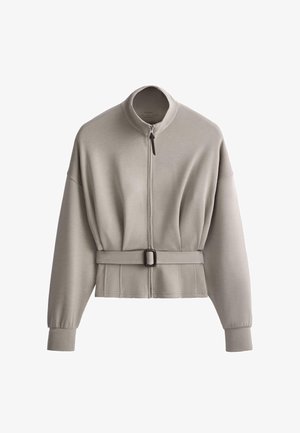 Jachetă cu fermoar și mâneci lungi, gri deschis, cu guler înalt și curea reglabilă în talie, confecționată dintr-un material moale.
