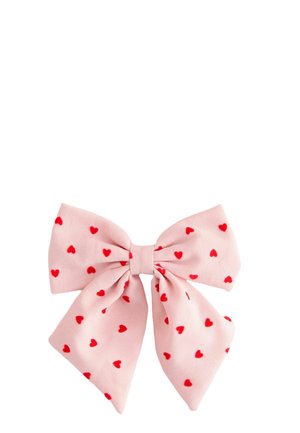 Pink fabric bow with red heart patterns evenly distributed across the entire bow on a white background.