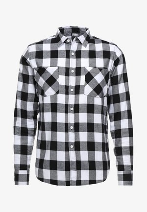 Musta-valkoinen ruudullinen napitetta paita, jossa on pitkät hihnat, kaksi rintataskua ja tavallinen kaulus. Valmistettu pehmeästä kankaasta.