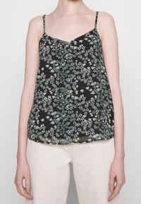 Camisole noire à fleurs avec bretelles ajustables, mettant en avant un motif délicat de petites fleurs bleues et vertes sur un tissu léger.