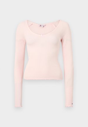 Haut ajusté à manches longues en tissu côtelé rose doux. Présente un décolleté en scoop, un ourlet effiloché et un petit nœud rose en accent au niveau de la poitrine.