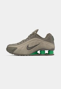 Baskets Nike de couleur vert olive avec une tige lisse, des détails perforés, des accents noirs et un amorti au talon vert. Design léger et épuré.
