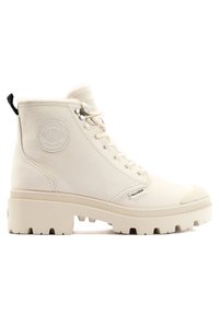 Bottes de cheville en textile beige avec une finition texturée, bout rond, semelle plate et patch logo sur le côté. Comprend des lacets et une languette.