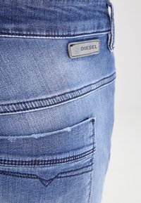 Ljusblå denimjeans med en synlig bakficka. Har en Diesel-märkeslabel och kontrasterande sömmar längs sömmarna.
