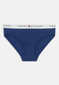 Σκούρο μπλε βαμβακερό εσώρουχο με λευκή ελαστική ζώνη μέσης που φέρει το όνομα της επωνυμίας "TOMMY HILFIGER" και το λογότυπο σε κόκκινες και μπλε αποχρώσεις.