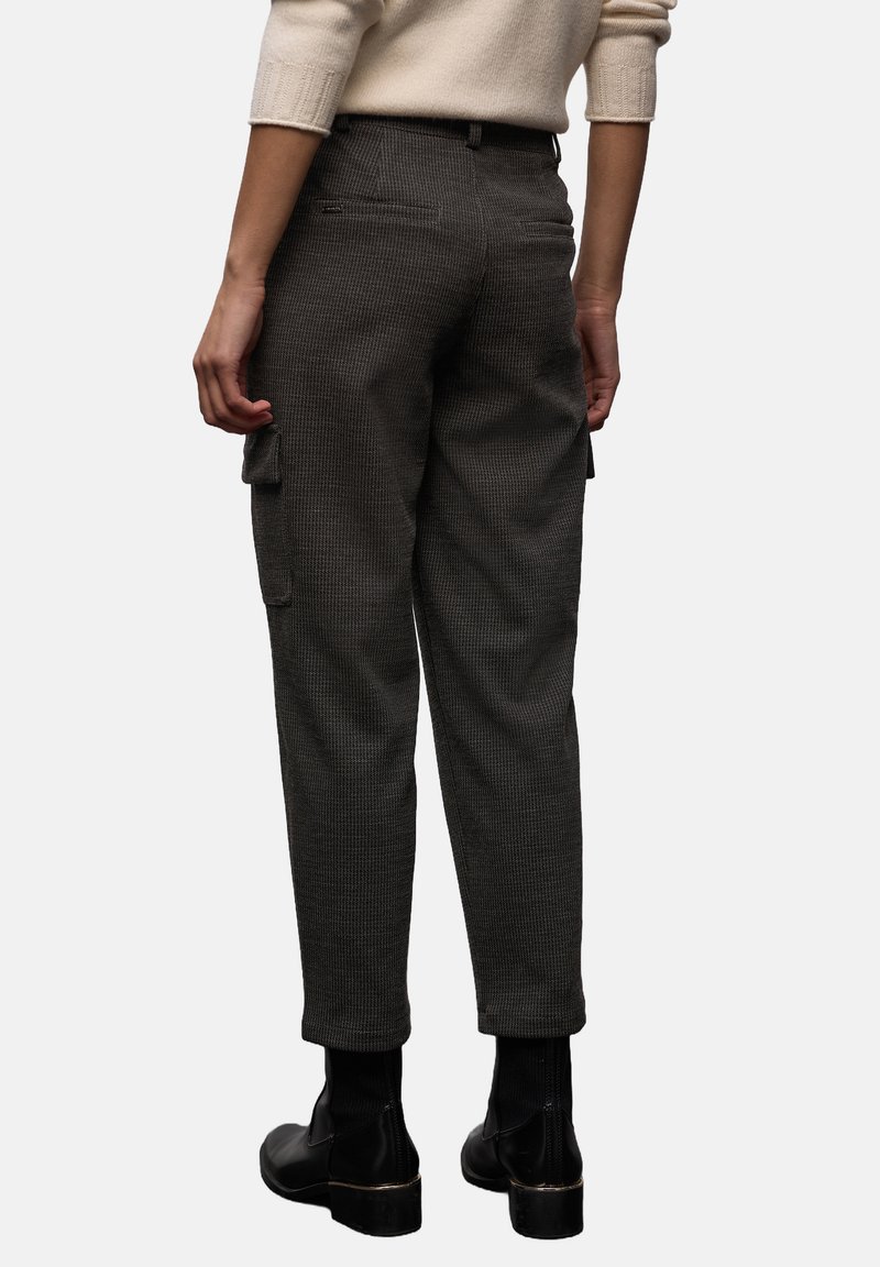 Cargo-broeken van een getextureerde donkergrijze stof, met zijzakken en een taps toelopende pasvorm. Draag ze met zwarte enkellaarzen.